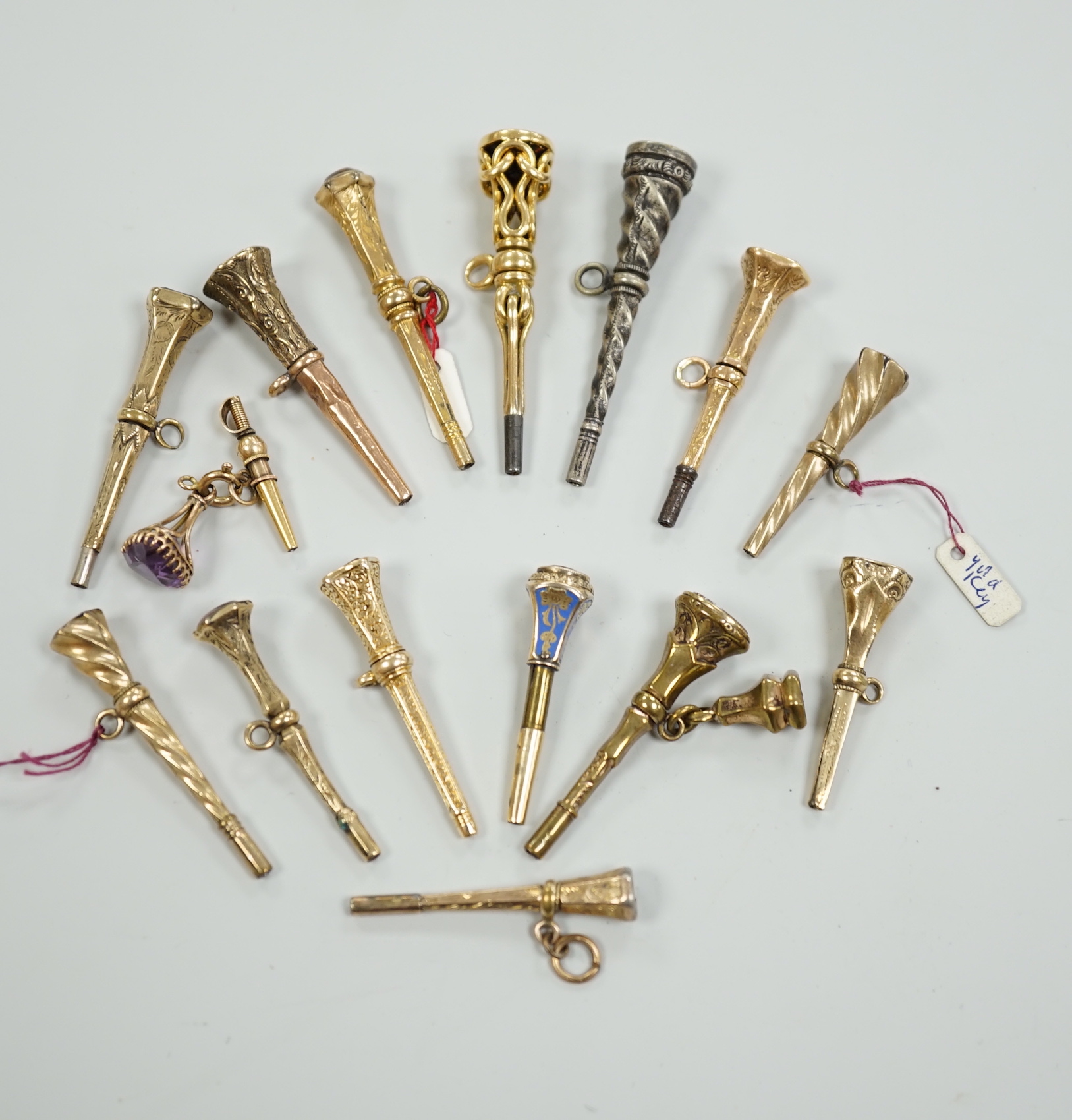 Fifteen assorted 19th century mainly yellow metal overlaid and gem set watch keys, including bloodstone, citrine and white chalcedony and one with enamel, mostly of trumpet form, largest 51mm.